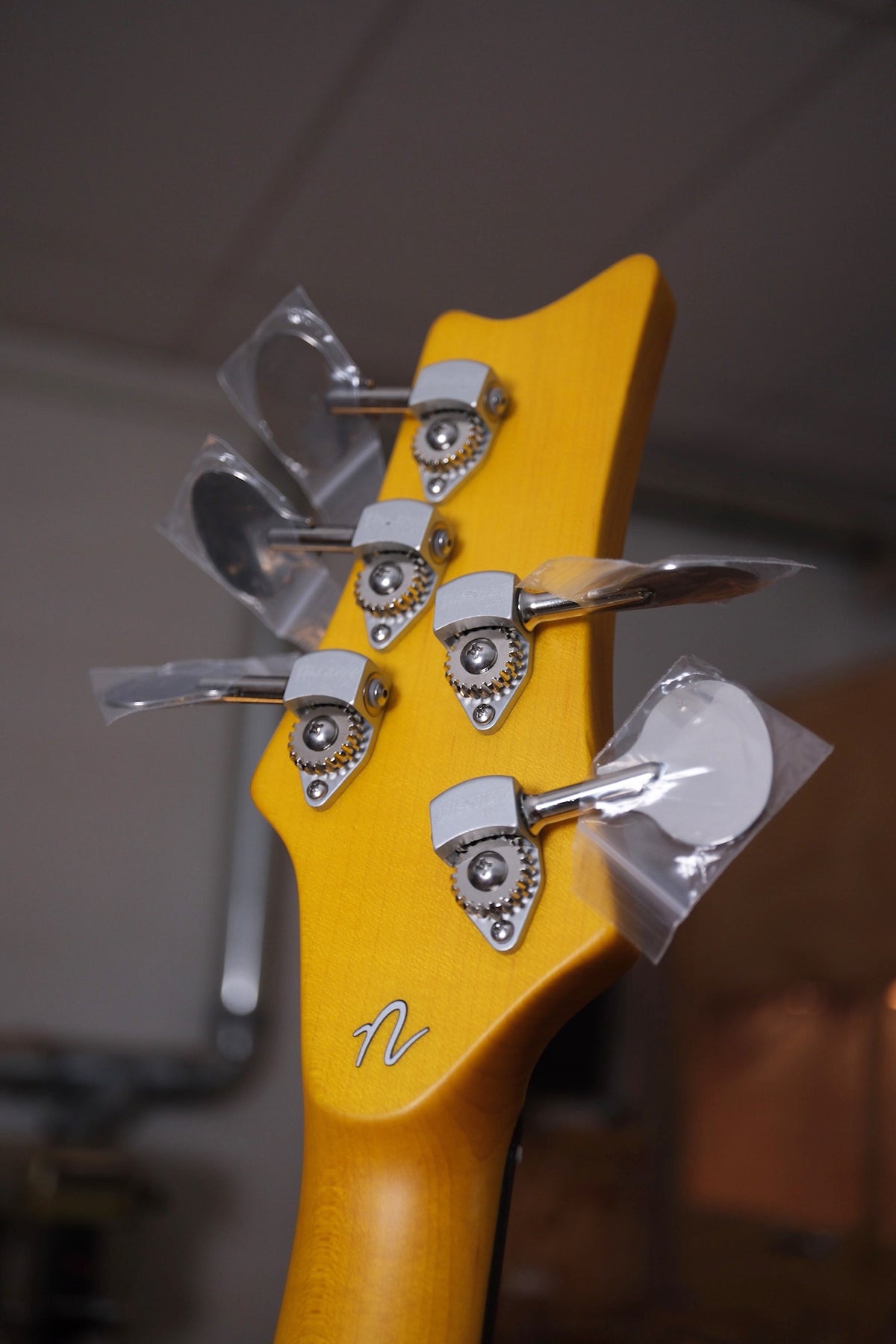 photo of the back of the Acinonyx V Short Scale Bass Guitar - Aztec Gold headstock showing the Nordstrand 'N' at the volute
