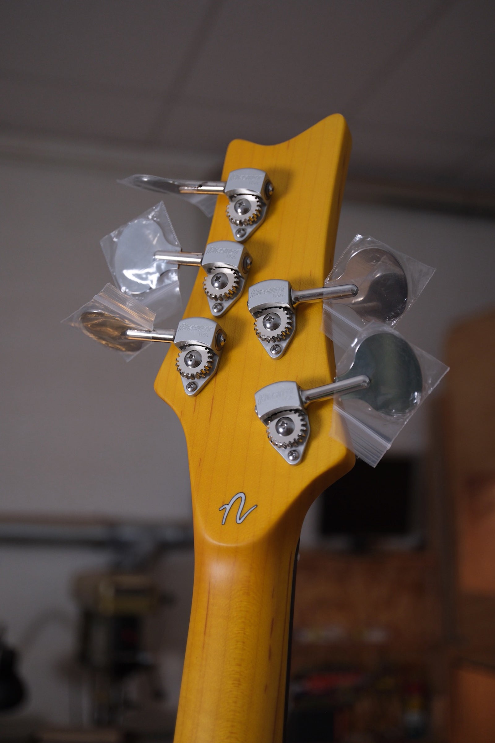 Photo of the back of the headstock of the Acinonyx V Short Scale Bass Guitar - Seafoam Green with the Hipshot Lollipop Ultralight Tuners